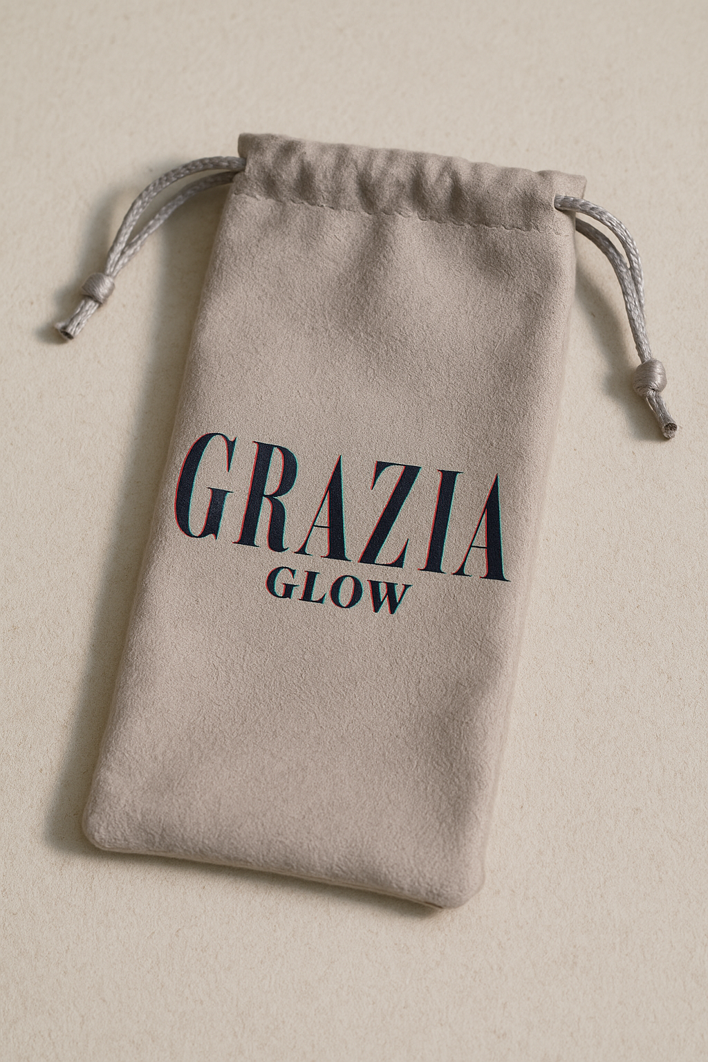 A beige drawstring bag with the text "GRAZIA GLOW" printed on it.